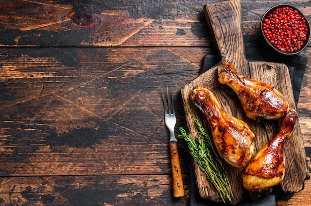 Muslos de pollo a la parrilla BBQ sobre una tabla para cortar madera