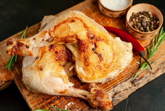 muslos de pollo a la parrilla con especias y hierbas, listos para cocinar sobre un fondo de piedra.