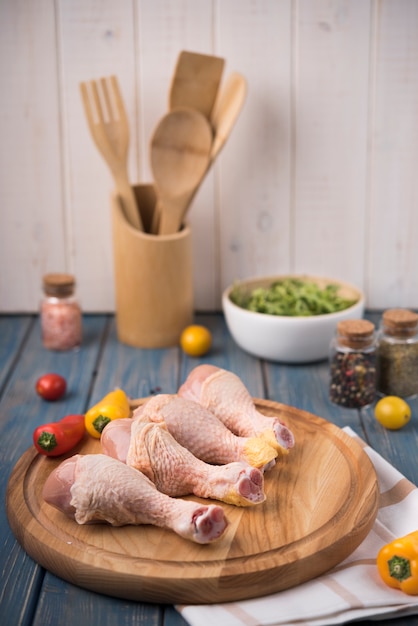 Muslos de pollo sobre tabla de madera con pimientos