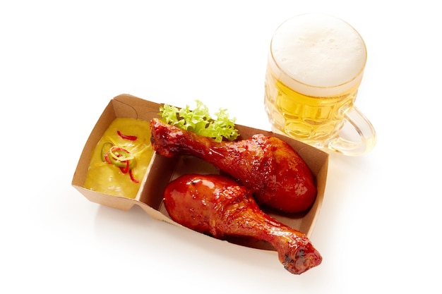 Muslos de pollo y vaso de cerveza en la mesa