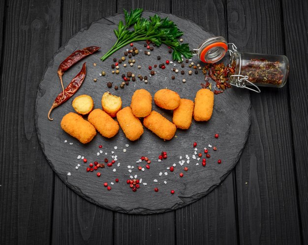 Mussarela frita, mordidas de queijo cheddar, bolas com ketchup em uma tábua de pedra rústica