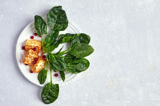 Mussarela halloumi de requeijão frito com espinafre verde e mirtilo em uma mesa de concreto cinza