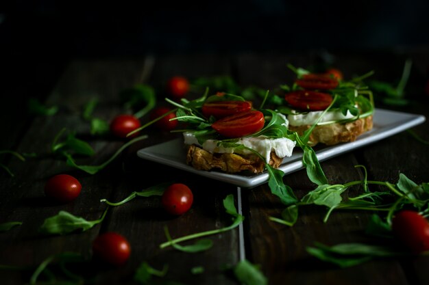 Mussarela, rúcula e tomate cereja bruschetta em uma mesa rústica