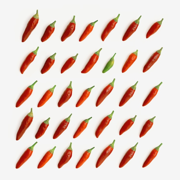 Muster aus kleinen Paprikaschoten auf weißem Hintergrund, eine grüne Paprika unter allen roten, nicht wie alle anderen