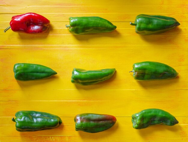 Foto muster der roten und grünen paprika über gelbem tabellenhintergrund