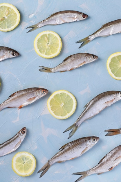 Muster des kleinen Fisches mit Zitronenscheiben auf einer blauen Oberfläche, Draufsicht, vertikale Ausrichtung