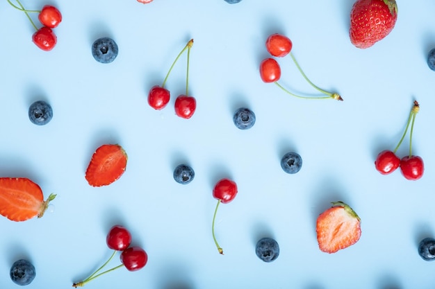 Muster mit Erdbeeren, Kirschen und Himbeeren auf blauem Hintergrund