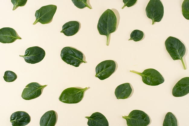 Muster von frischen Babyspinatblättern auf gelbem Hintergrund, vegetarisches Essen