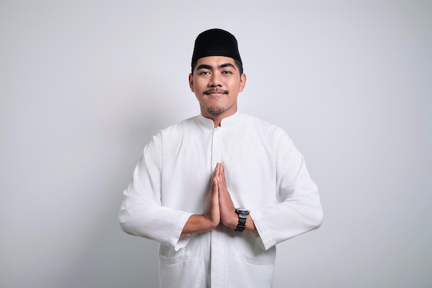 Foto musulmán asiático vestido con ropa blanca sonriendo para saludar durante la celebración del ramadán y eid al fitr