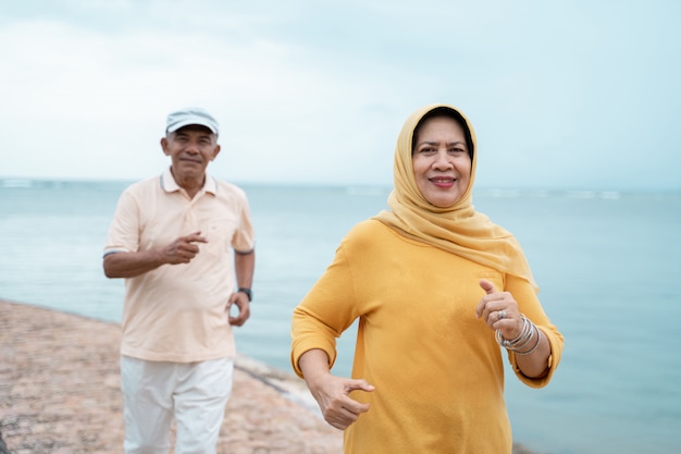 Musulmana pareja de ancianos entrenamiento y correr en la playa