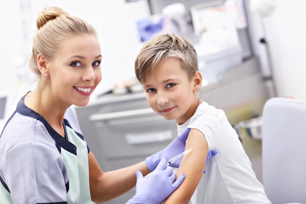 mutiger kleiner Junge, der mit einem Lächeln eine Injektion oder einen Impfstoff erhält