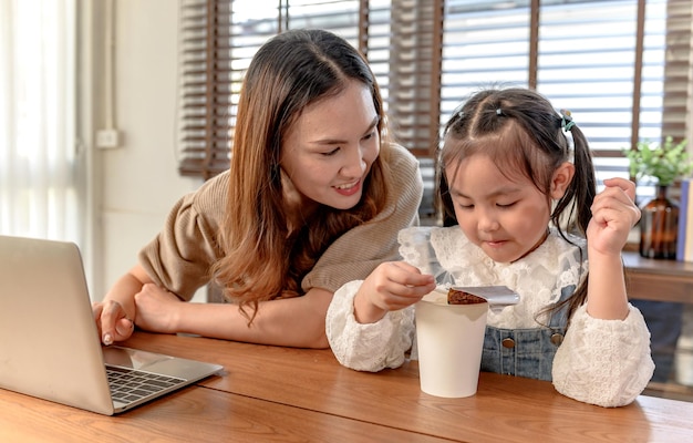 Mutter arbeitet und unterrichtet Tochter für Online-Lernen zu Hause. Lebensstil der Familienzusammengehörigkeit und neue Normalität nach Covid-19.