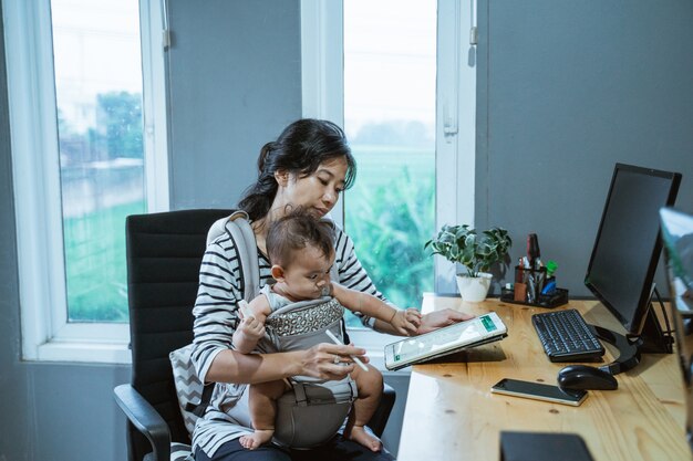 Mutter babysittet ihr Baby während der Arbeit