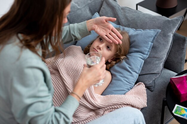 Mutter berührt die Stirn ihrer Tochter, um zu sehen, ob sie Fieber hat.