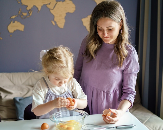 Mutter bringt einem kleinen Kind das Kochen bei, während sie Zeit zu Hause verbringt