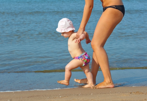 Mutter bringt ihrer Tochter bei, zum Strand zu gehen.