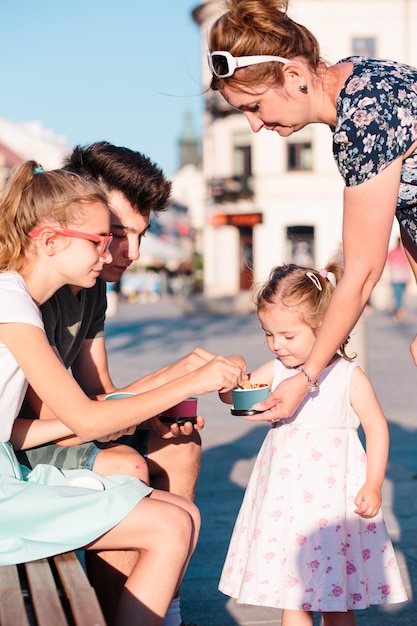 Mutter, die an einem sonnigen Tag in der Stadt Kindern Essen gibt