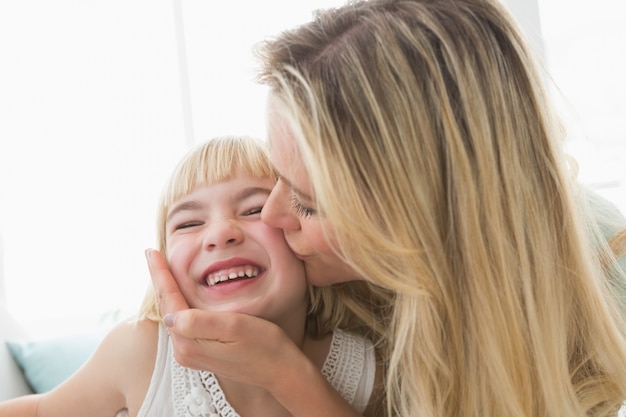 Mutter, die glückliche Tochter auf der Backe küsst