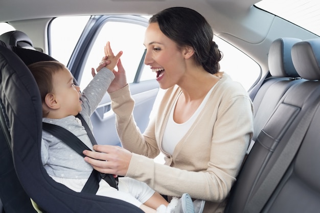 Mutter, die ihr Baby im Autositz sichert