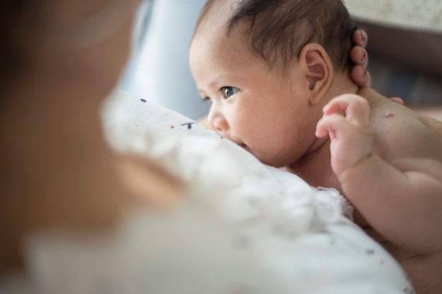 Mutter, die ihr neugeborenes Baby neben Fenster stillt