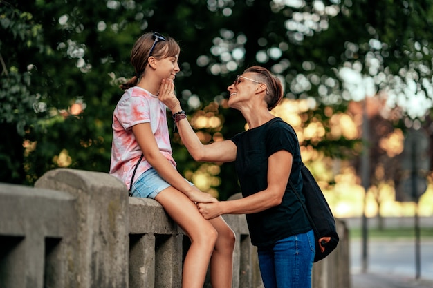 Mutter, die mit der Tochter sitzt am Zaun spricht