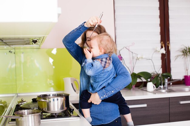 Mutter, die mit ihrem kleinen Sohn Abendessen kocht. Mutter gibt ihrem Sohn beim Kochen Suppe zum Probieren