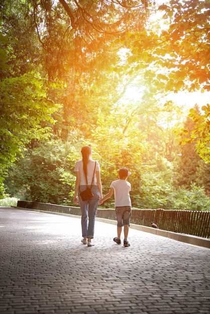 Mutter, die mit ihrem Sohn im Park spazieren geht Alleinerziehende Mutter Nanny und das Kind Geschwister Vertikaler Rahmen