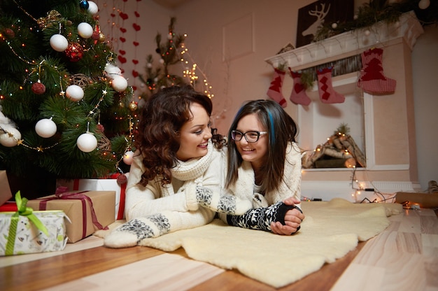 Mutter, die nahe bei Tochter nahe Weihnachtsbaum liegt.