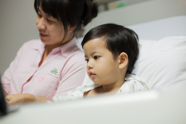 Mutter, die seinem Sohn auf einem Krankenhausbett eine Geschichte liest.