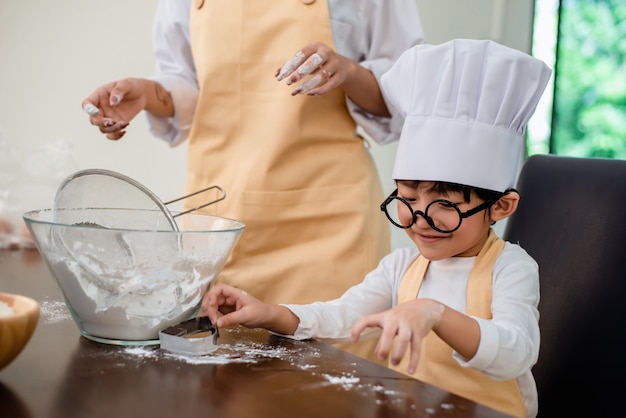 Mutter, die Sohn für das Kochen von Essen unterrichtet. Der tägliche Lebensstil von Mutter und Kind zu Hause. Asiatische Familie zusammen in der Küche.