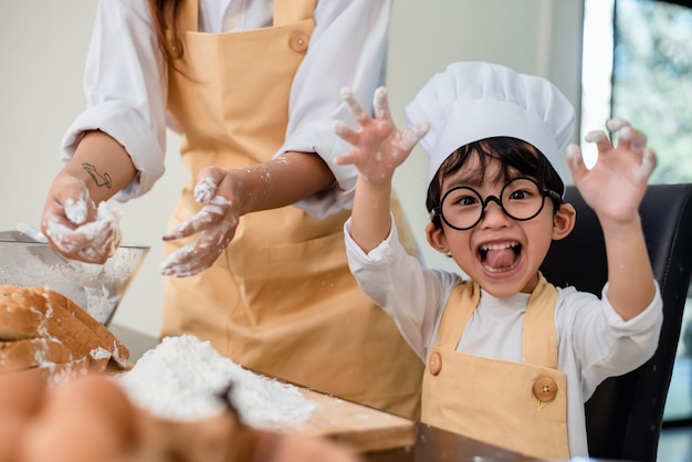 Foto mutter, die sohn für das kochen von essen unterrichtet. mutter und kind täglicher lebensstil zu hause. asiatische familie zusammen in der küche.