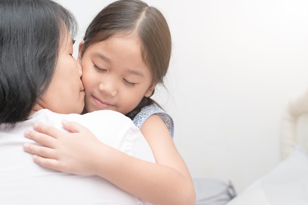 Mutter, die umarmt und ihr Tochter-, Liebes- und Sorgfaltkonzept küsst