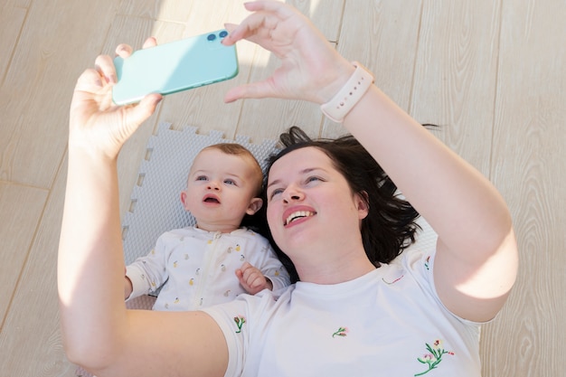 Mutter, die Zeit mit ihrem Babysohn nimmt ein selfie mit einem Telefon verbringt