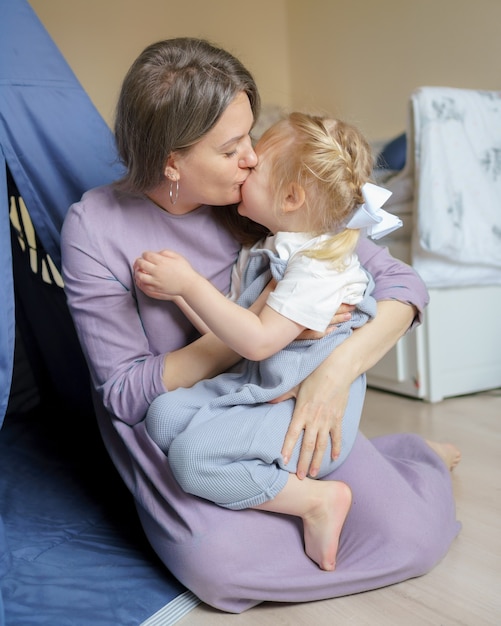 Mutter drückt der kleinen Tochter Liebe aus, während sie im Kinderzimmer sitzt sitting