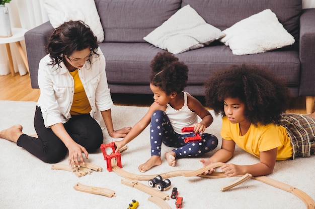 Mutter Eltern spielen mit Kindern, die lernen, Puzzle-Spielzeug zu Hause zu lösen. Kindermädchen, das schwarze Leute im Wohnzimmer sucht oder Kinderbetreuung.
