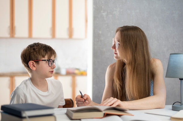 Mutter erklärt ihrem Sohn, wie er seine Hausaufgaben macht. Junger Tutor arbeitet mit einem Studenten. Häuslicher Unterricht.