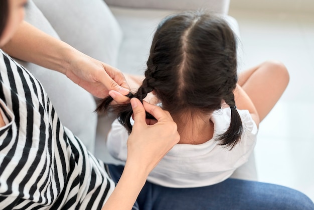 Mutter flechtet Haare ihrer Tochter