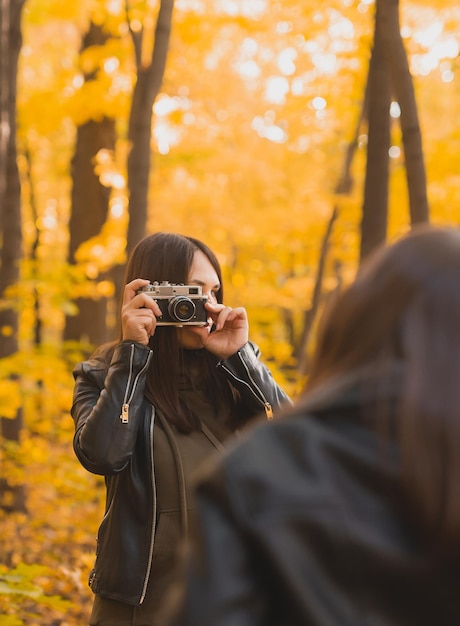 Mutter fotografiert ihre charismatische Tochter auf Retro-Kamera im Herbst Park Hobbys und Freizeit Co