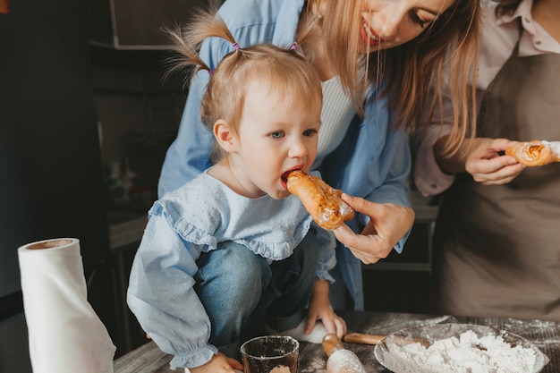 Mutter füttert das Baby ein Brötchen in der Küche.