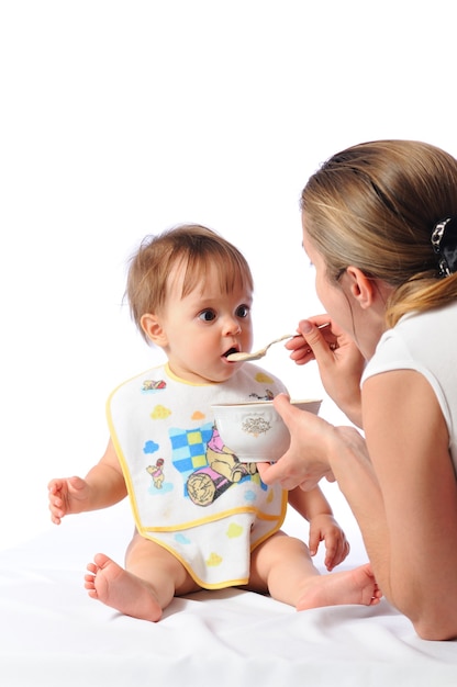 Mutter füttert kleines einjähriges Mädchen von Babynahrung oder Brei mit Löffel