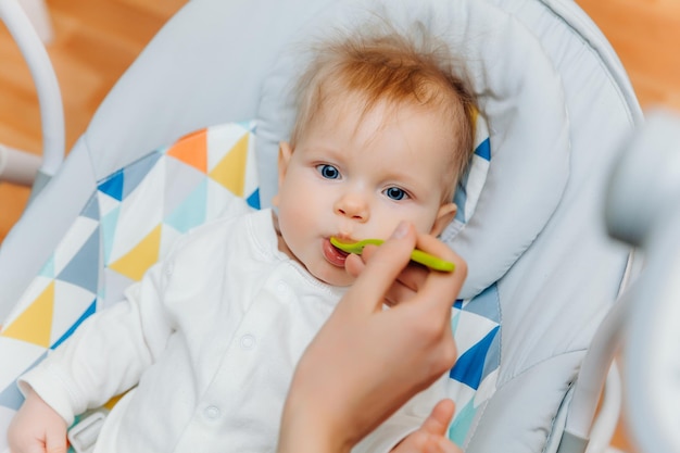 Mutter gibt Baby FruchtsoßeMutter füttert Baby auf HochstuhlBabynahrung