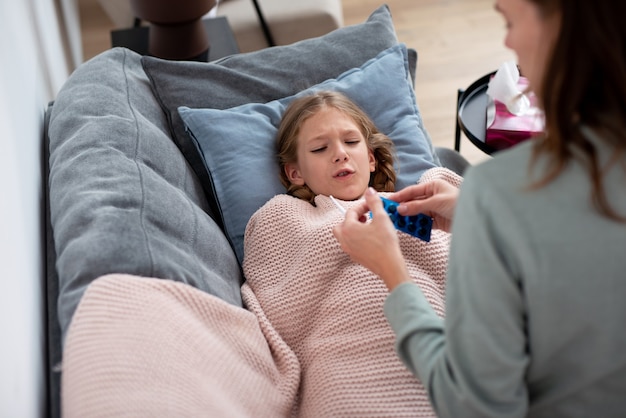 Mutter gibt einer erkälteten Tochter bittere Pillen