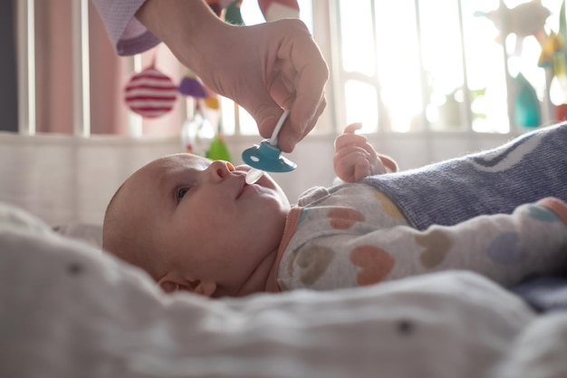 Mutter gibt ihrem kleinen Baby einen Schnuller, um sie zu beruhigen