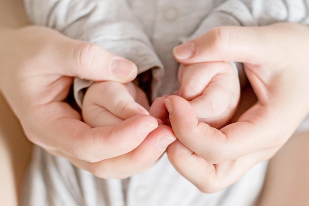 Mutter hält die Hände eines neugeborenen Babys Emotionale Verbindung mit dem Baby Ukrainisches neugeborenes Baby in den Armen der Mutter hautnah
