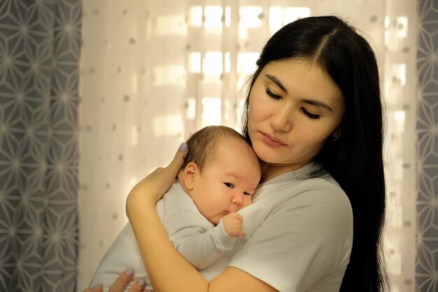 Mutter hält ein Kind ein Baby in ihren Armen, das Kind will schlafen