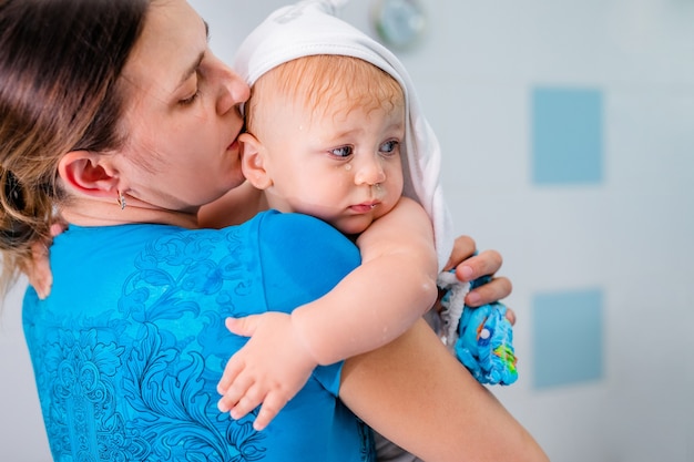 Mutter hält ihr baby nach dem baden in den armen.