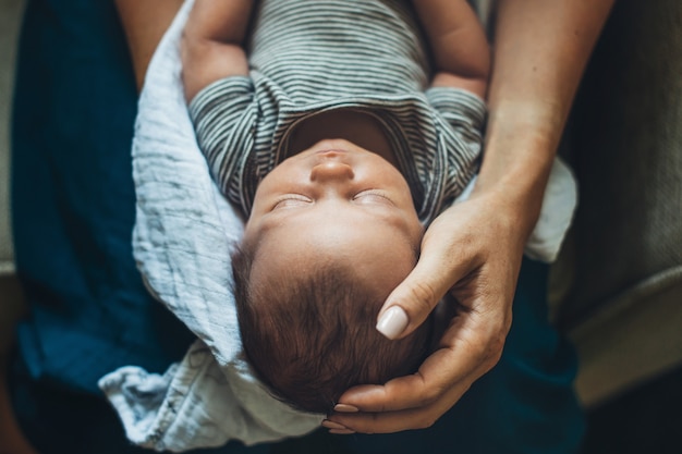 Mutter hält ihr neugeborenes Baby auf Beinen und berührt ihren Kopf