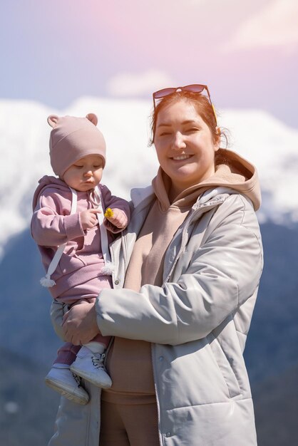 Mutter hält ihre kleine Tochter im Arm, die mit Löwenzahn spielt