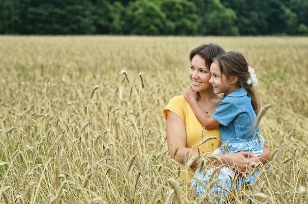 Mutter hält ihre Tochter auf dem Feld posiert