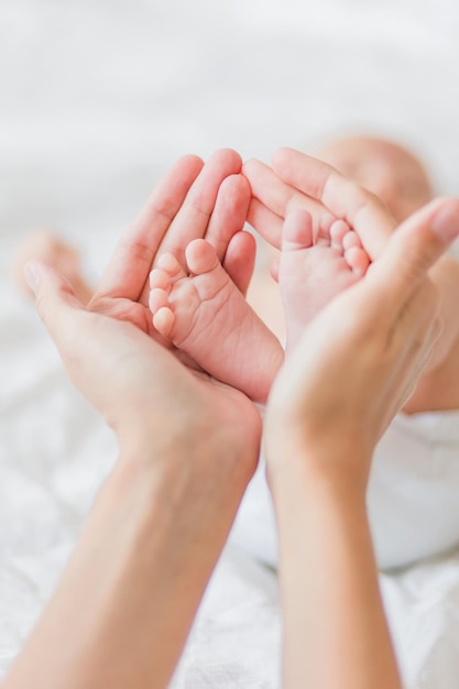 Mutter hält neugeborene Babys barfuß kleine Füße in der Hand der Frau gemütlicher Morgen zu Hause